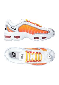 Baskets blanches avec des accents orange et jaune, présentant un design texturé, des zones en maille et un amorti d'air visible dans les semelles.