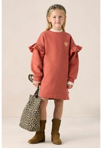 Rostfarbiges Kleid mit Rüschensäumen und Herzdetails. Braune Knöchelstiefel und eine Tasche im Leopardenmuster. Glatte Stoffqualität, lässiger Stil.