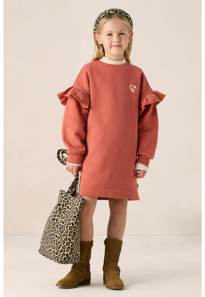 Rostfarbiges Kleid mit Rüschensäumen und Herzdetails. Braune Knöchelstiefel und eine Tasche im Leopardenmuster. Glatte Stoffqualität, lässiger Stil.