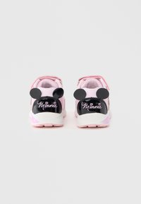 Chaussures de sport roses avec des accents en cuir verni noir, ornées d'oreilles de Mickey Mouse et de l'inscription « Minnie » sur le talon. Fermeture à velcro et semelle coussinée.