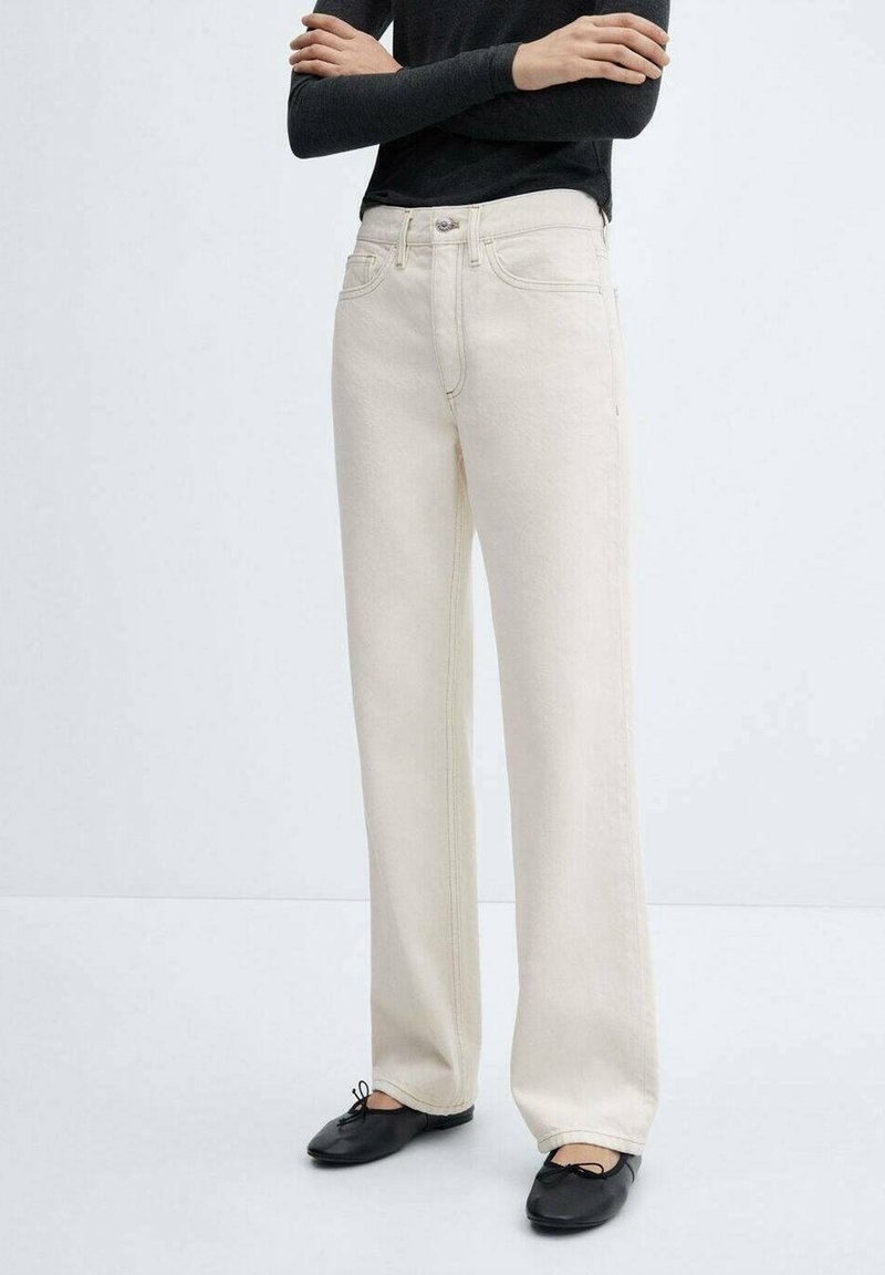 Jeans de pierna ancha color crema, hechos de mezclilla con costuras visibles y bolsillos frontales; combinados con zapatos negros.