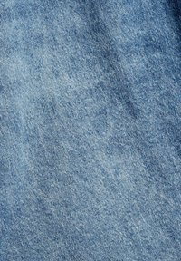 Texture de tissu en denim bleu clair avec des motifs de tissage diagonaux et de subtiles variations de couleur sur l'ensemble du matériau.