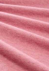 Rosa Stoff mit einer weichen, strukturierten Oberfläche, die sanfte Falten und ein einheitliches Muster zeigt. Das Material wirkt leicht und leicht meliert.