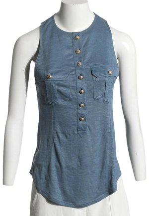Blouse bleue sans manches avec boutons devant et deux poches poitrine, présentée sur un torse de mannequin blanc.