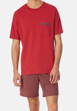 Rotes Baumwoll-T-Shirt mit einer Tasche, die ein gemustertes Detail aufweist, kombiniert mit gemusterten Shorts in Rot und Weiß, beide leicht und lässig.