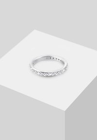 Úzky strieborný prsteň s radom malých priehľadných kameňov pozdĺž hornej polovice, označený "925" vo vnútri prsteňa.