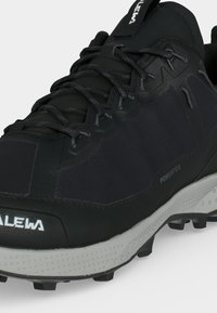 Μαύρο και γκρι παπούτσι πεζοπορίας με υφή στην σόλα, μπροστινό κορδόνι και σήμανση "Powertex" στο πλάι για χρήση σε εξωτερικά μονοπάτια.