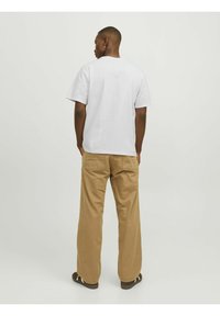 Hvid bomulds T-shirt med korte ærmer og rund hals, parret med beige brede bukser med baglommer og en løs pasform.