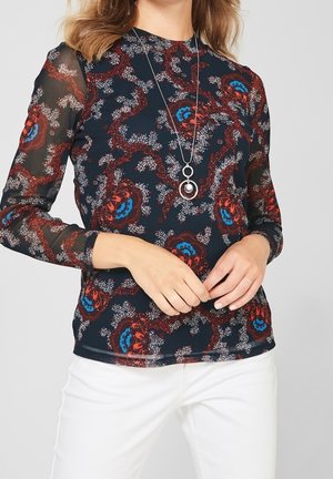 T-shirt à manches longues avec une base bleu marine foncé et un motif floral en rouge, bleu et blanc. Manches en mesh transparent et col rond.