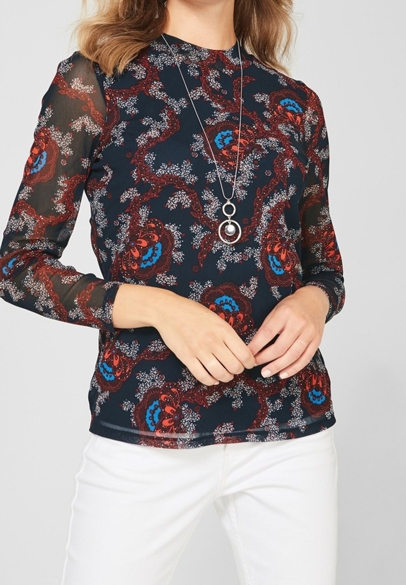 Långärmad topp med en mörk marinbas och blommönster i röd, blå och vit. Transparenta nätärmar och rund halsringning.