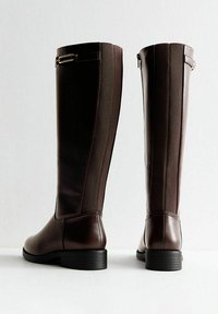 Pair of tall dark brown leather boots with elastic side panels, low heels, and decorative buckle straps at the top back.