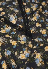 Tissu noir avec imprimé floral jaune et bleu, ornée d'une bordure en dentelle noire en forme de V.