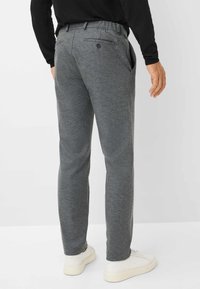 Pantalons gris en tissu texturé, dotés de poches latérales et d'un détail à bouton au dos, associés à des baskets blanches.