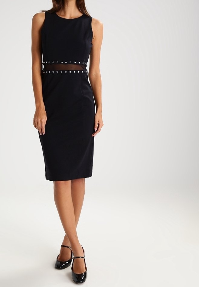 Robe noire ajustée sans manches, avec une découpe en maille et des accents cloutés à la taille. Tissu lisse avec une silhouette arrivant aux genoux.