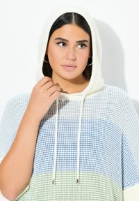 Gebreide hoodie met een witte capuchon, voorzien van blauwe en groene horizontale strepen, aansnoerkoordjes en een textuurdesign. Strakke pasvorm rond de halslijn.