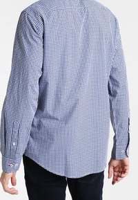 Blauw-witte geblokte langesleeve shirt met een gebogen zoom; heeft knoopmanchetten en een gladde stoftextuur.