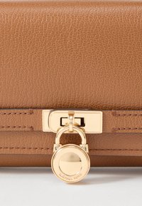 Bolso de mano de cuero marrón texturizado con detalle de cierre de hardware dorado y broche rectangular. Cuenta con costuras sutiles a lo largo de los bordes.