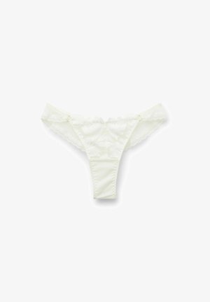 String en dentelle blanche avec motifs floraux, bords festonnés et une taille lisse agrémentée de détails en matériel décoratif.