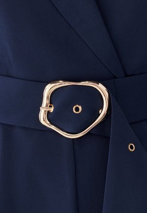 Maritiem stof met een gestructureerde afwerking, voorzien van een gouden, abstractvormige riemgesp en zijsluiting. Elegante tailoring met een gestructureerde silhouet.