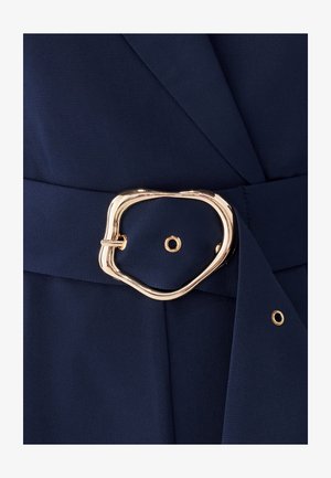 Maritiem stof met een gestructureerde afwerking, voorzien van een gouden, abstractvormige riemgesp en zijsluiting. Elegante tailoring met een gestructureerde silhouet.