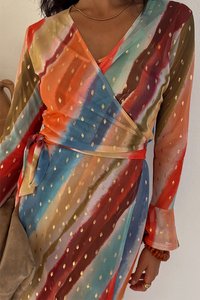 Spalvota susiaučiama suknelė su ryškiomis juostomis raudonos, oranžinės, mėlynos ir žalios spalvų bei auksinių taškelių raštu, pagaminta iš permatomos medžiagos, su surišama juosmens dalimi.