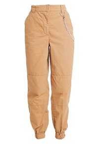 Pantalons cargo ajustés en coton beige clair avec une taille élastique, des poches latérales et un détail en chaîne métallique d'un côté.