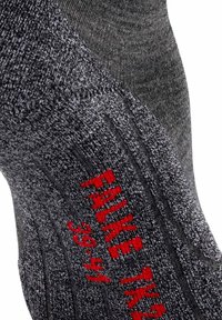 Calcetín gris de punto con textura de canalé, con detalles de texto en rojo. Material suave con un ajuste ceñido, adecuado para uso casual.