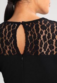 Top nero con schiena in pizzo trasparente con motivo leopardato e un piccolo apertura a chiave, completato da una chiusura con zip.