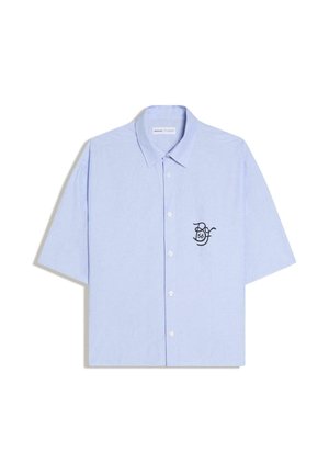 Vaaleansininen, lyhythihainen napillinen kauluspaita, jossa vasemmassa rinnassa pieni musta kirjailtu logo, jossa lukee "56".