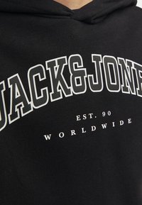 Black hoodie featuring bold white text that reads "JACK&JONES" with "EST. 90" and "WORLDWIDE" printed in smaller font below.