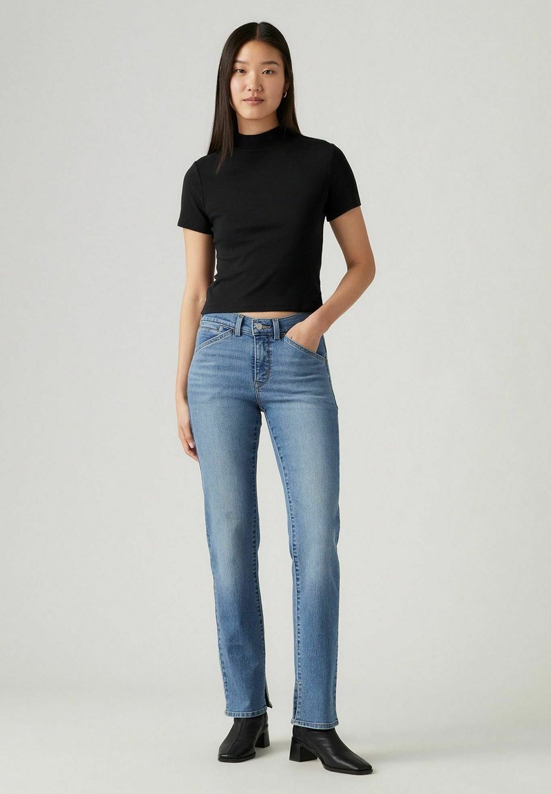 Top negro de manga corta, jeans rectos azules, combinados con botas de tobillo; textura suave, colores sólidos y un diseño ajustado.