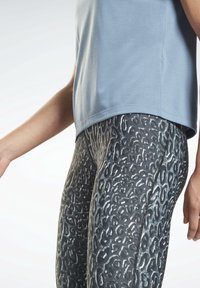 Ljusblå träningströja med lös passform, i kombination med svarta leggings med ett silverfärgat leopardmönster och en mjuk textur.