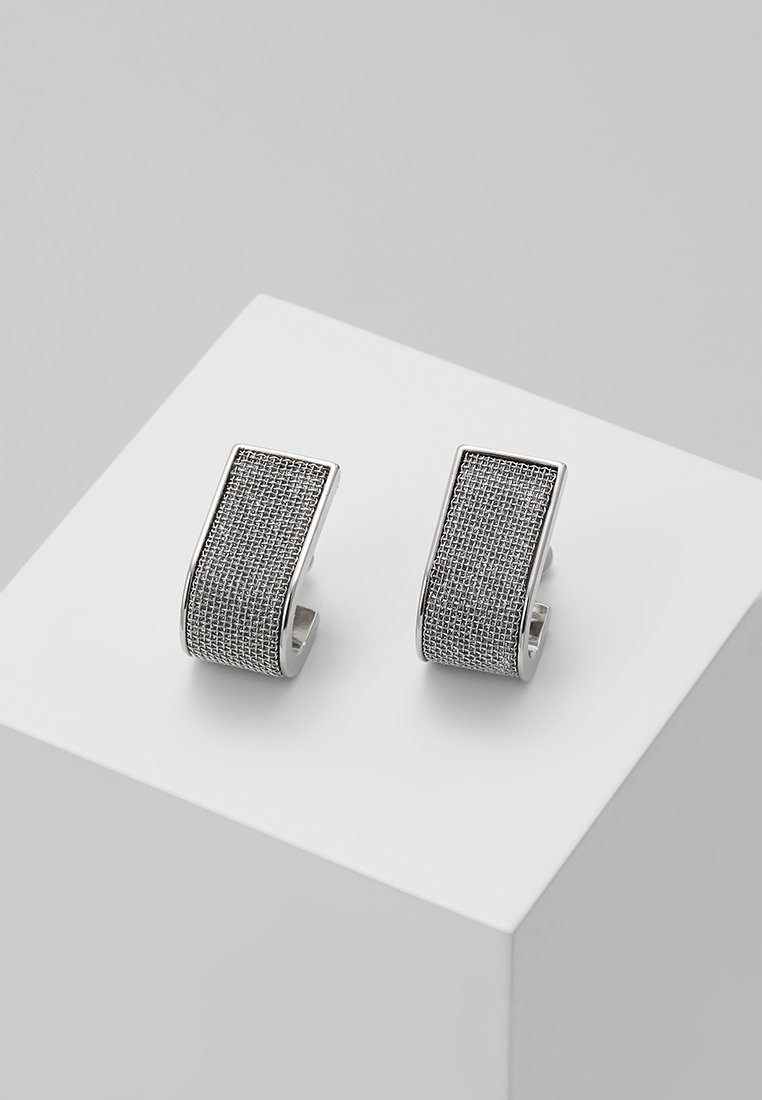 Paquet de boucles d'oreilles créoles rectangulaires ton argent avec motif en maille texturée exposées sur un socle blanc.
