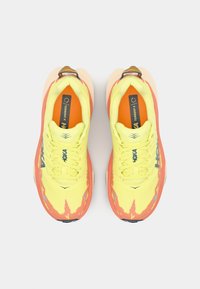 Baskets de sport jaune vif avec des accents orange, en tissu en maille, semelle en caoutchouc texturée et détail de logo contrastant sur le côté.