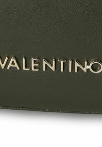 Borsa in pelle verde con logo "Valentino" in rilievo color argento, dalla texture liscia e design minimalista.