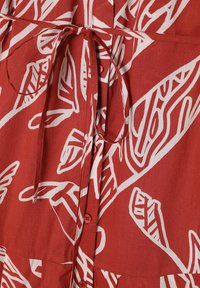 Abito rosso in tessuto con motivi a foglia bianchi, dotato di cintura in vita, chiusura a bottoni e finitura testurizzata. Materiale leggero e traspirante.