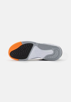 Sål på en sneaker med sort, grå og orange slidbane med teksturerede grebsmønstre og et synligt Nike Air-logo i hvidt i midten.