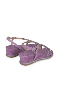 Sandales en suède violet avec un talon compensé et des lanières ornées de cristaux. Boucle de cheville ajustable, doublure intérieure lisse.