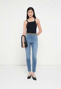 Mustast sobivast sporditopist, kõrge vöökohaga helesinistest teksadest koos leopardimustrilise vöö, must käekott ja mustad terava ninaga kingad. Minimalistlik disain.