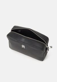 Beauty case in pelle nera con hardware della cerniera argentata, esterno testurizzato e logo in evidenza sul fronte. Parte superiore aperta che mostra l'interno.