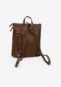 Mochila de piel marrón con un asa en la parte superior, correas ajustables, bolsillo lateral con cremallera y detalle de costura en contraste. Textura suave.