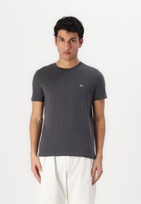 Tricou gri cu mânecă scurtă, din bumbac, cu guler rotund și un detaliu mic cu logo pe piept. Textură netedă, formă ajustată.