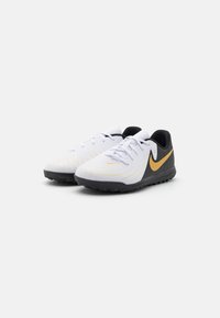 Zapatillas deportivas blancas con parte superior texturizada, detalles en amarillo, contrafuerte negro y suela de goma diseñada para ofrecer tracción.