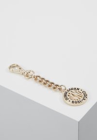 Zlatý klíčový řetízek s kulatým př�ívěskem, který nese vyražený text a vzory. Odkaz ve tvaru článků s pevným zapínáním pro bezpečné použití.