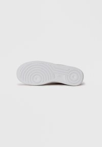 Sola de borracha branca de um ténis Nike mostrando padrões de tração circulares e o logótipo da Nike ao centro.