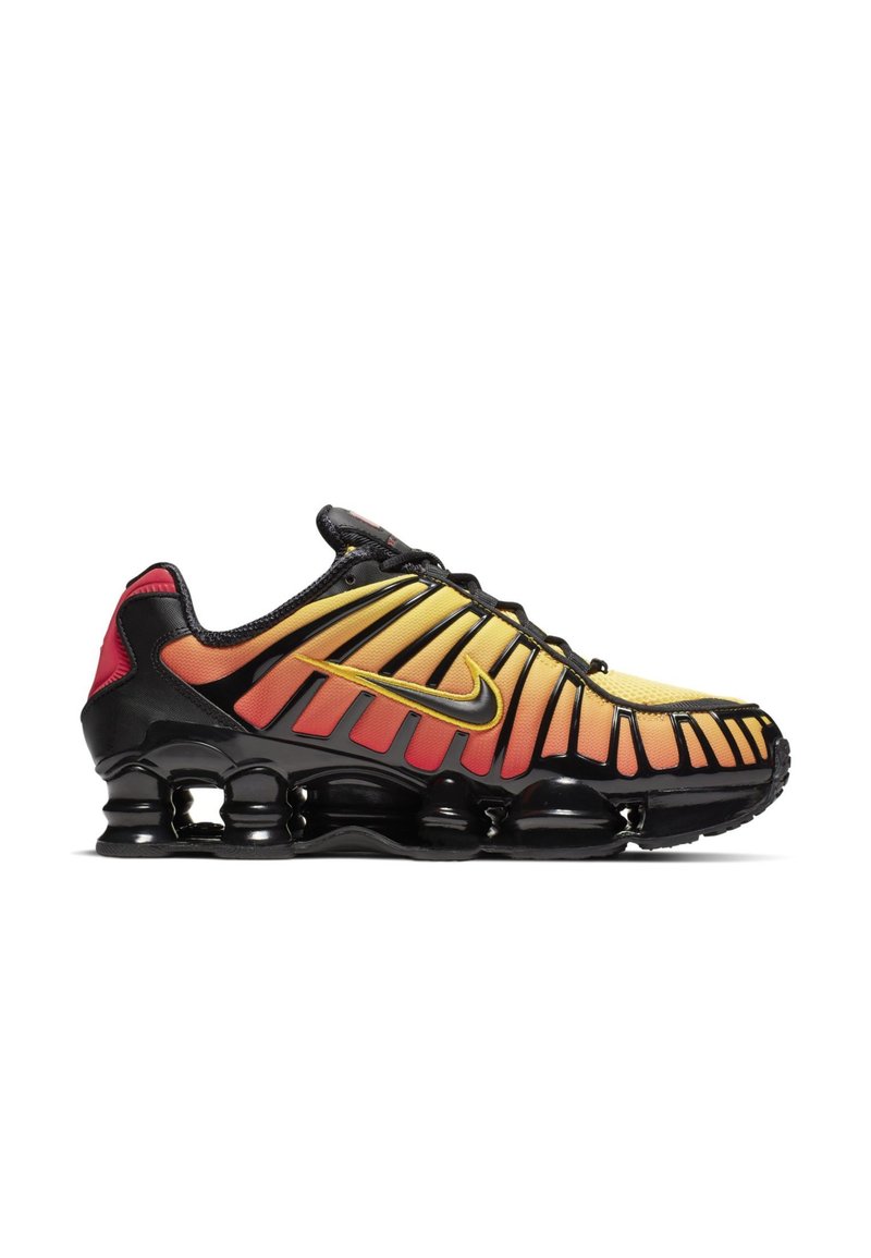 Baskets Nike noires et jaunes avec des accents en dégradé orange-rouge, tige en maille, semelle adhérente et système de cushioning SHOX distinctif.