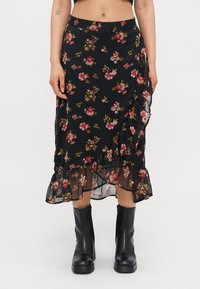 Svart blomstret skjørt med rysjet kant, med rosa og grønne mønstre. Laget av lett stoff, kne-lengde design, kombinert med svarte støvler.