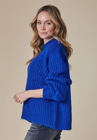 Blauer Strickpullover mit lockerer Passform, gerippter Textur und breiten Ärmeln. Features einen Rundhalsausschnitt und seitliche Schlitze am Saum.