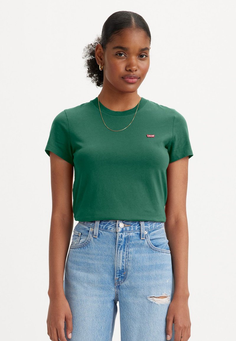 Groene katoenen T-shirt met een ronde hals, korte mouwen en een rood Levi's-logo op de borst, gecombineerd met lichtblauwe hoge taillejeans.