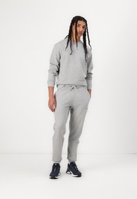 Gray sweatshirt and sweatpants set, made of soft fabric, featuring a classic crew neck, elastic waistband, and tapered leg design.